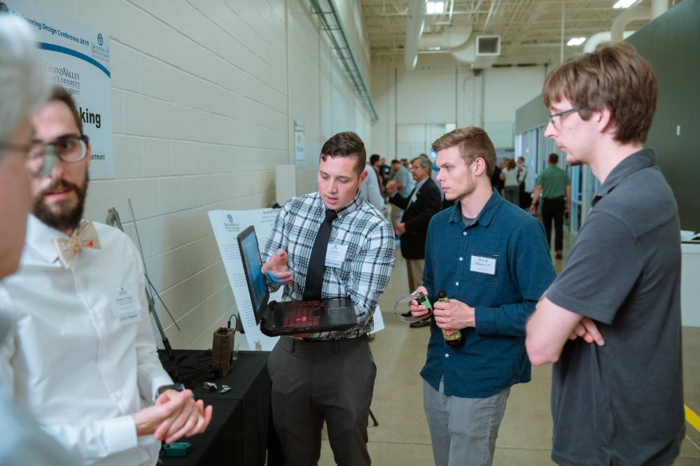 A student explaining something on a laptop to guests at the Engineering Design Project Preview